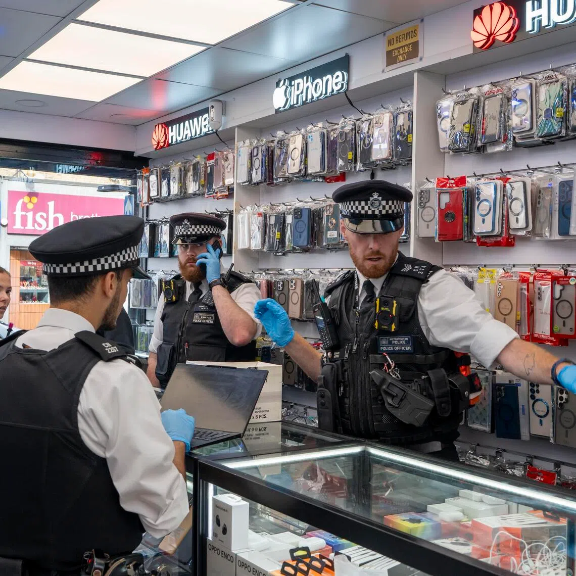 Police officers search a secondhand phone shop in north London on Sept 25, 2025.