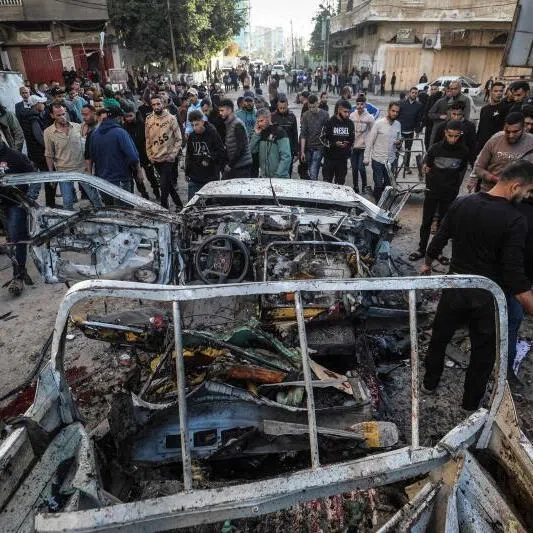 People gather around a destroyed Palestinian police jeep that was targeted by an Israeli air strike in Nuseirat refugee camp in the central Gaza Strip on March 22, 2026.