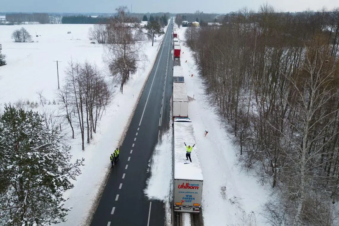 FILE PHOTO: A truck driver from Ukraine waves from his truck roof while waiting in a long queue to cross the Polish-Ukrainian border at the Dorohusk-Jagodzin crossing, in Okopy, Poland, December 4, 2023. REUTERS/Kuba Stezycki/File Photo