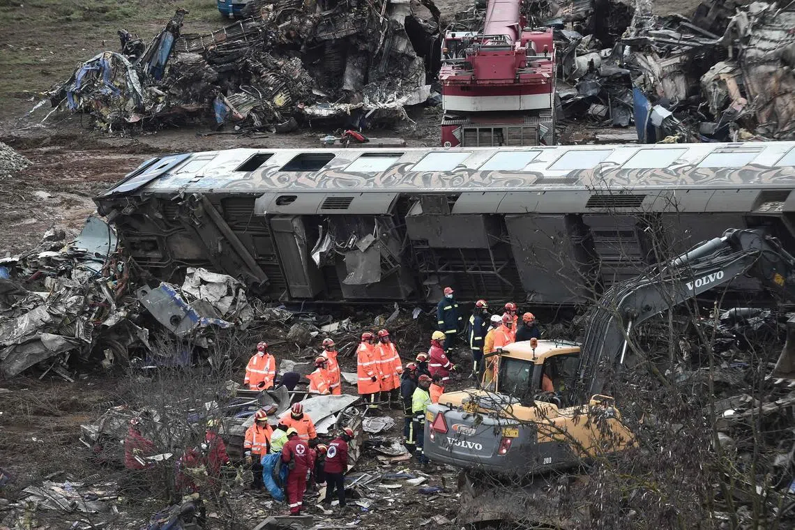 Police and emergency crews examine the debris of a crushed wagon, two days after a passenger train collided head-on with a freight train in Greece.