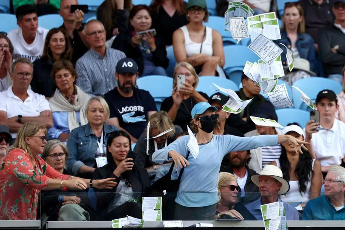Tennis - Australian Open - Melbourne Park, Melbourne, Australia - January 22, 2024 A woman throws flyers about Palestine, amid the ongoing conflict between Israel and the Palestinian Islamist group Hamas, during the fourth round match between Britain's Cameron Norrie and Germany's Alexander Zverev REUTERS/Eloisa Lopez