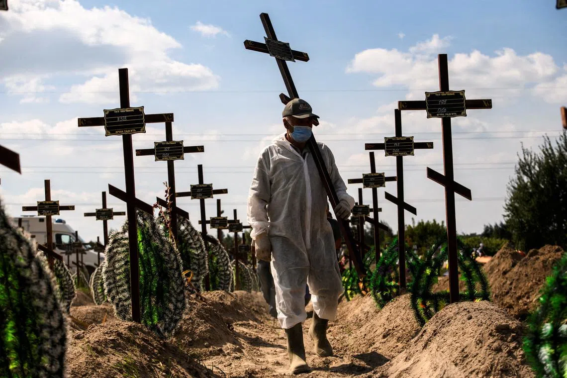 A volunteer places a cross with a number on the grave of one of the unidentified people killed by Russian troops during a mass burial ceremony in the town of Bucha, in the Kyiv region of Ukraine, on Sept 2, 2022.  