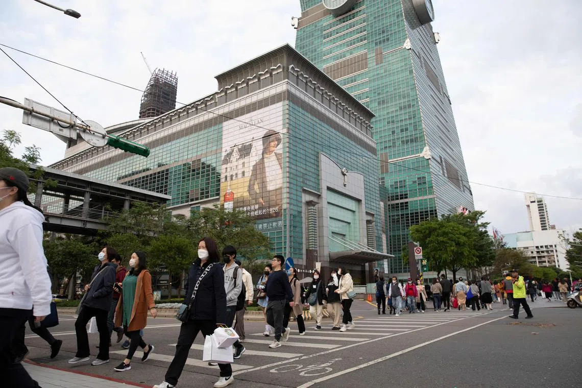People walk along the street next to the Taipei 101 building in Taipei as China launched military drills around the island, on April 8, 2023. 
