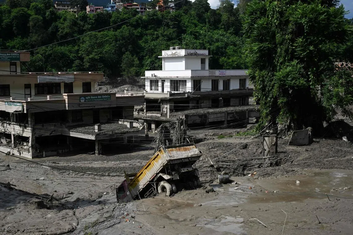 A truck and buildings partially submerged by mud following flash floods and a landslide disaster in Devghat, in Nepal’s Nuwakot district.