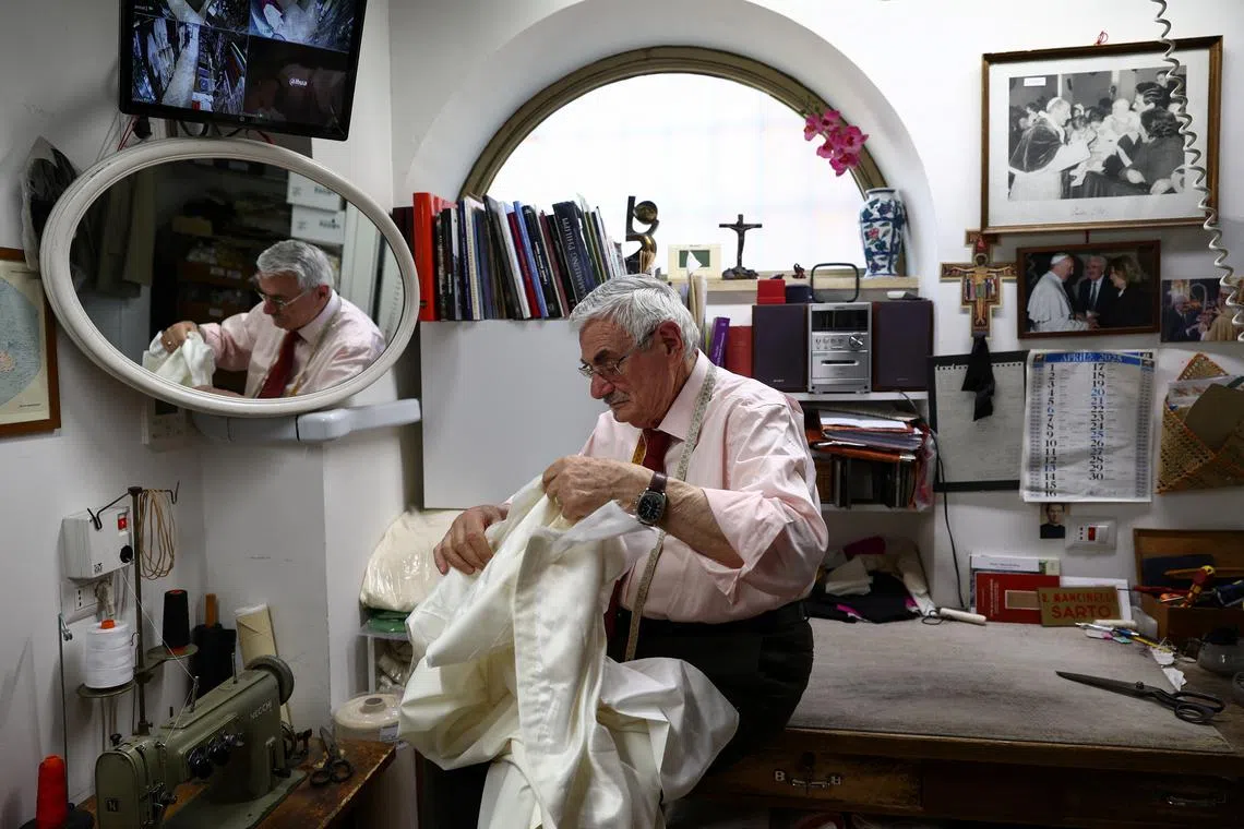 Clerical robe tailor Raniero Mancinelli works on a white papal cassock at his liturgical vestments shop near the Vatican, in Rome, Italy, April 29, 2025. REUTERS/Guglielmo Mangiapane