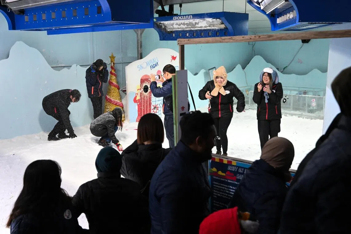 Teacher Joshua Heng (centre with a cellphone) taking a photo of his family (top left) playing with snow.