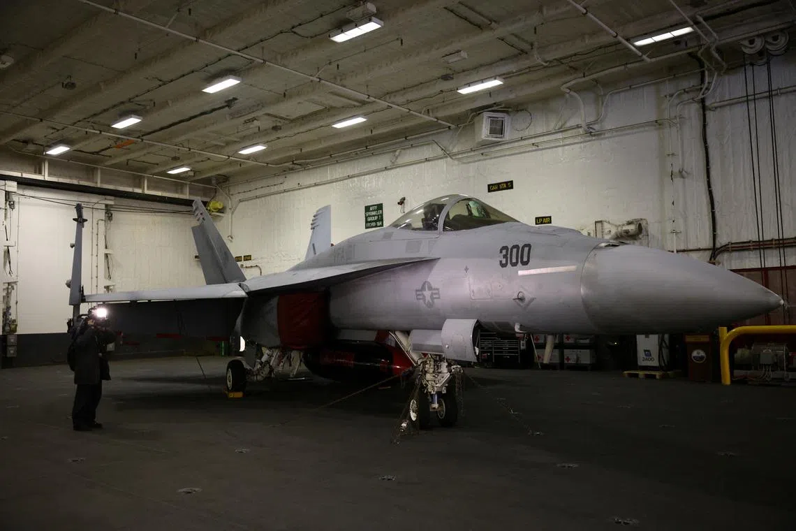 A member of the media films an F-18 fighter jet in the hangar of the U.S. Aircraft Carrier USS Gerald R. Ford while anchored in the Solent near Gosport, Britain, November 17, 2022. REUTERS/Henry Nicholls