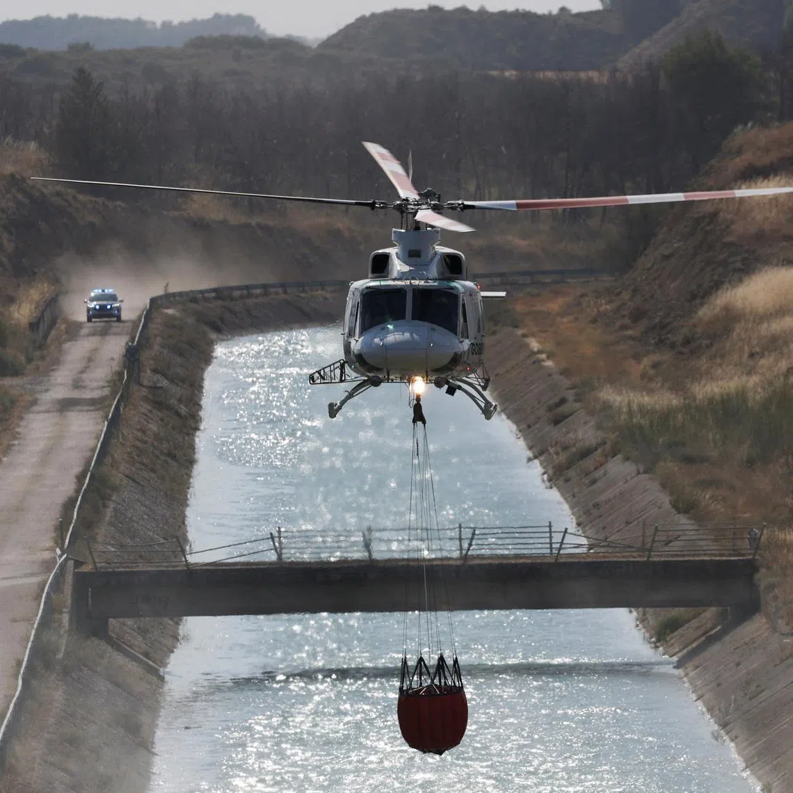 A firefighting helicopter loads water to battle wildfires affecting Zaragoza province, in Farasdues, Spain, on July 16.