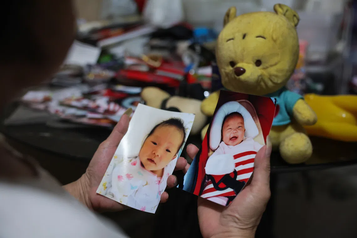 Megan Khung's grandmother, Madam Chua, looking at Megan's baby photos. Madam Chua still keeps her granddaughter's pictures and toys in her one-room rental flat.