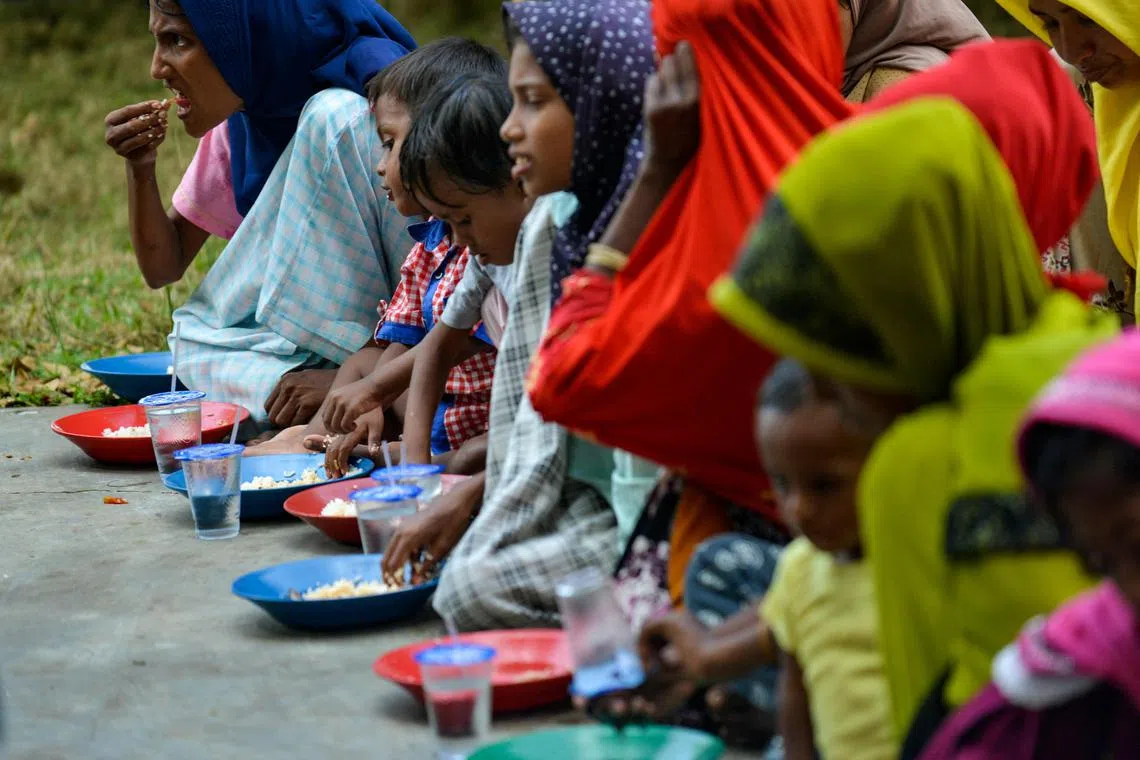 Rohingya refugees eat food in a temporary shelter following their arrival by boat in Laweueng, Aceh province on December 27, 2022. 