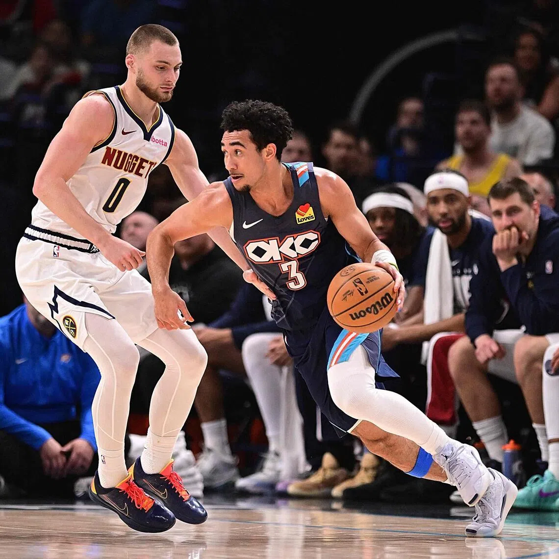 Jared McCain of the Oklahoma City Thunder handles the ball while being defended by Christian Braun of the Denver Nuggets during the first half at Paycom Center.