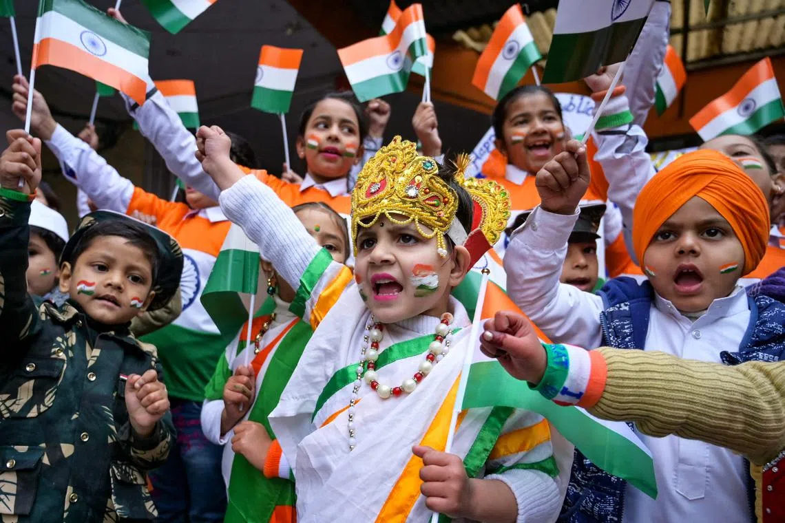 Children wearing outfits with India's national flag colours cheer during celebrations on the eve of the country's Republic Day.