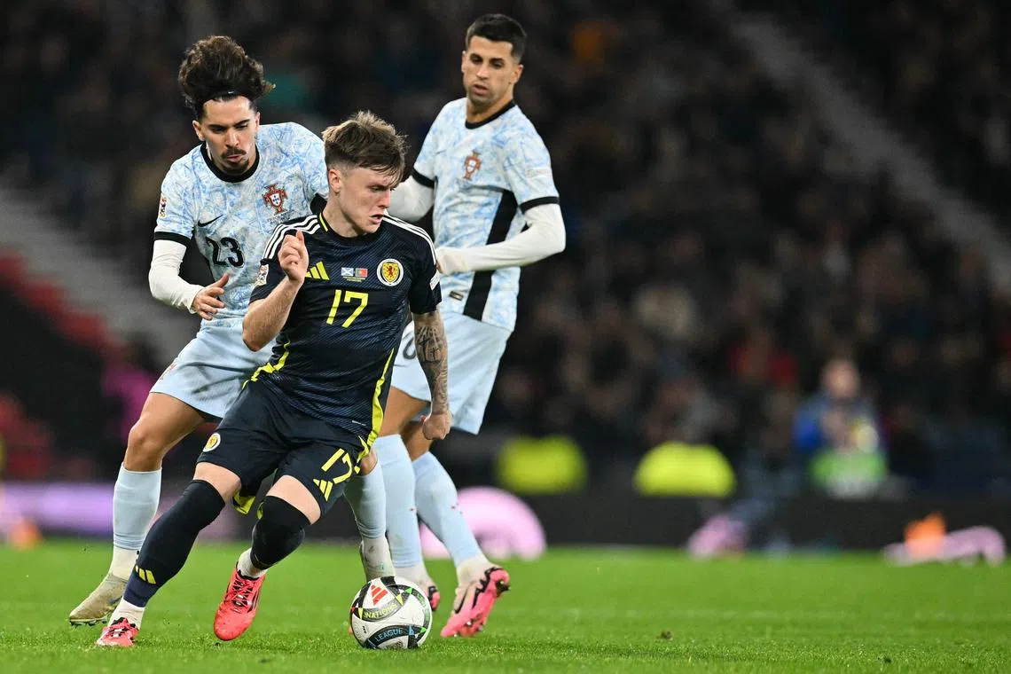 Portugal's midfielder Vitinha (left) fights for the ball with Scotland's midfielder Ben Doak at Hampden Park Stadium in Glasgow.