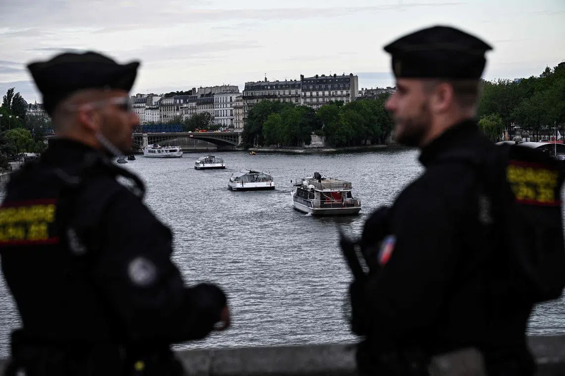 French gendarmes watch over boats from a fleet of 55 taking part in a technical navigation rehearsal on the Seine river for the opening ceremony of the Paris 2024 Olympic Games, in Paris, on June 17, 2024. It must shine, and make Paris and the athletes shine: but the Seine, expected star of the 2024 Olympics as the site of the opening ceremony and open water events, is suffering from unpleasant weather which is giving cold sweats to the organizers. 
