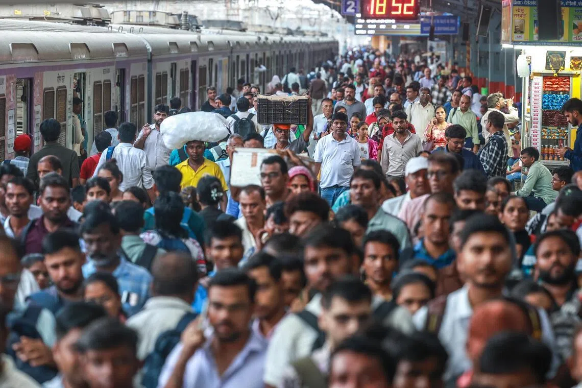 Commuters cross the platform after disembarking a local train at the railway station in Mumbai, India, on May 12, 2026.