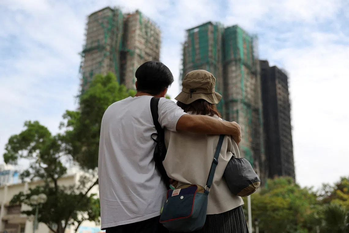 People look on near the Wang Fuk Court housing complex following the deadly fire.