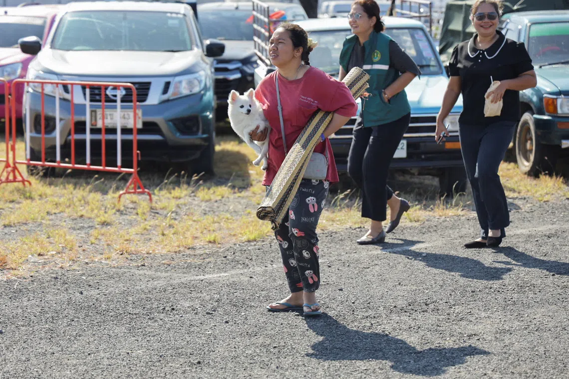 A woman carries a dog and a mat as she evacuates to a shelter, following fresh military clashes between Thailand and Cambodia along parts of their disputed border, in Buriram province, Thailand, December 8, 2025. REUTERS/Prajoub Sukprom