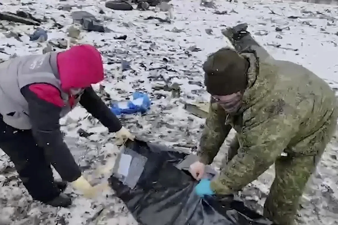 A still image from a Russian handout video shows what investigators say is a body being covered at the crash site, in Russia's Belgorod region.