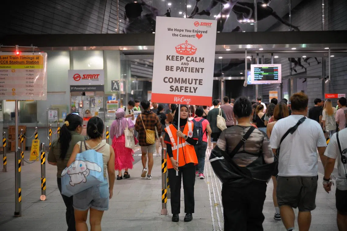 A staff from SMRT holds a sign to help with crowd control as people start to stream in from the first day of the Taylor Swift Eras Tour in Singapore on March 2, 2024.