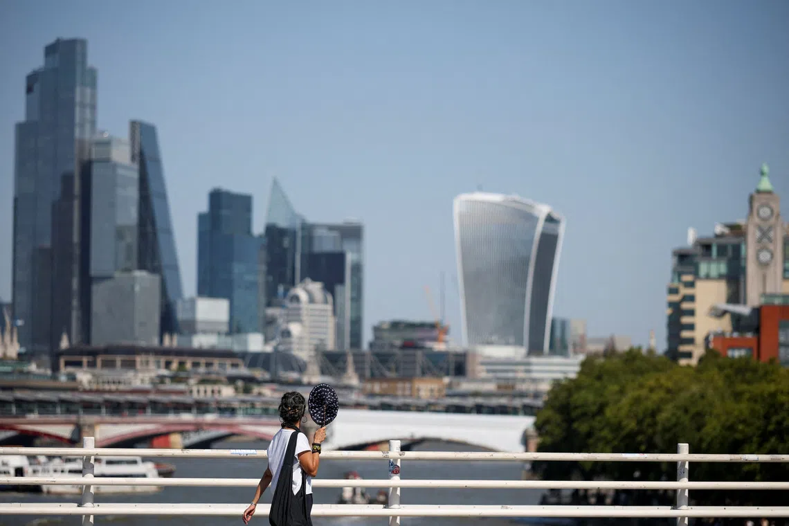 A woman walks across Waterloo Bridge, with the City of London financial district in the background, in London, Britain, August 13, 2026. REUTERS/Isabel Infantes/File Photo