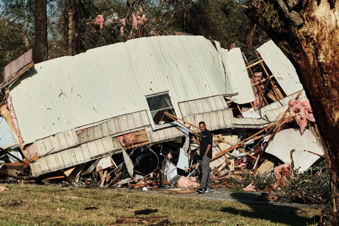 A man inspect a trailer home destroyed from a tornado touching down in Mount Vernon, Alabama.