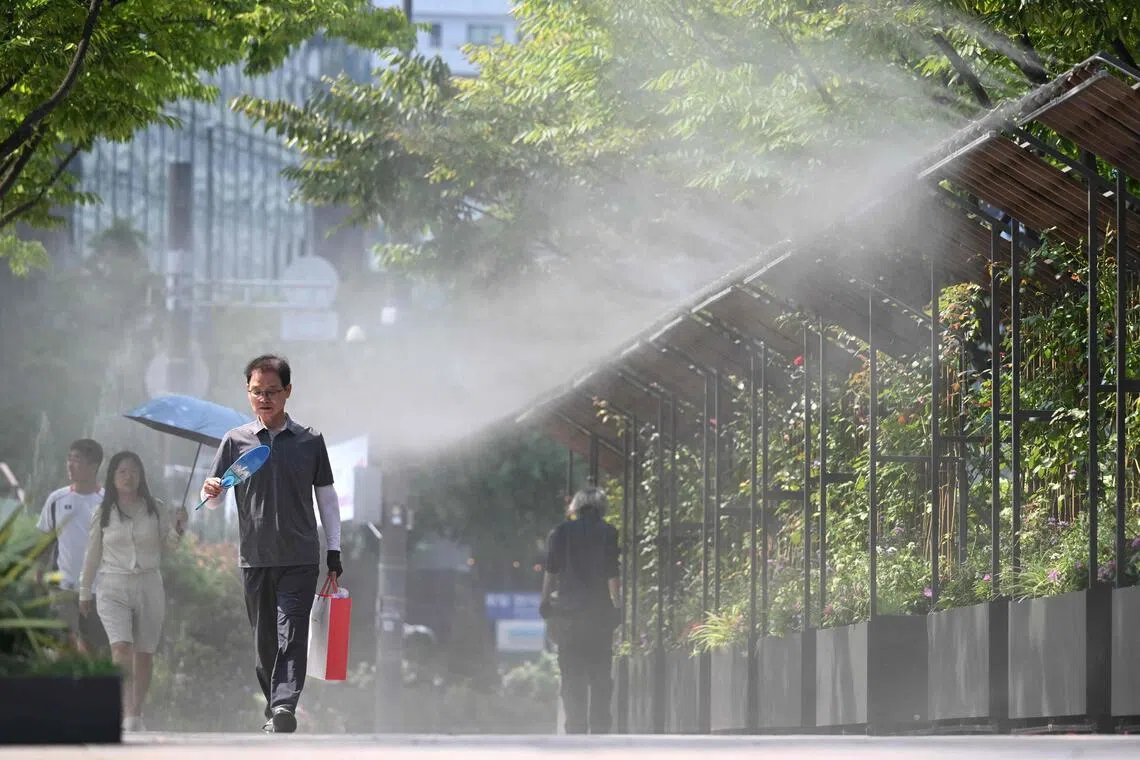 TOPSHOT - Pedestrians walk along a mist-spraying zone to cool off on a street in Seoul on August 3, 2026, as a scorching heat wave continues to grip South Korea. South Korea registered its highest temperature since records began more than a century ago on August 2, as authorities warned people to "immediately" stop all outdoor activities in affected areas. (Photo by Jung Yeon-je / AFP)