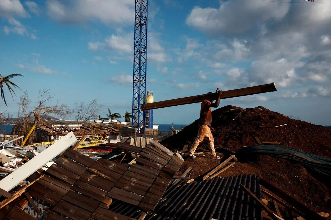 FILE PHOTO: A man cleans the debris around the destroyed houses in the aftermath of Cyclone Chido, in Mamoudzou, Mayotte, France December 20, 2024. REUTERS/Gonzalo Fuentes/File Photo
