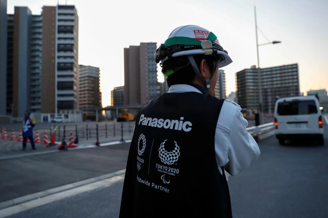 FILE PHOTO: A worker wears a jacket with the logo of Panasonic, Tokyo 2020 Olympic and Paralympic Games' partner, as he walks at an under-construction site of the Olympic villages in Tokyo, Japan March 25, 2020. REUTERS/Issei Kato