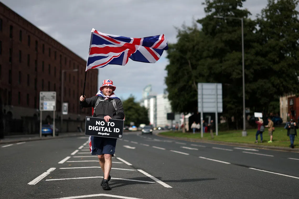 A protester holds a Union Jack flag and a sign during  a 'No to Digital ID' demonstration against the planned introduction of a government-issued digital ID for all British adults, near to the Labour Party Conference in Liverpool, Britain, September 28, 2025. REUTERS/Hannah McKay