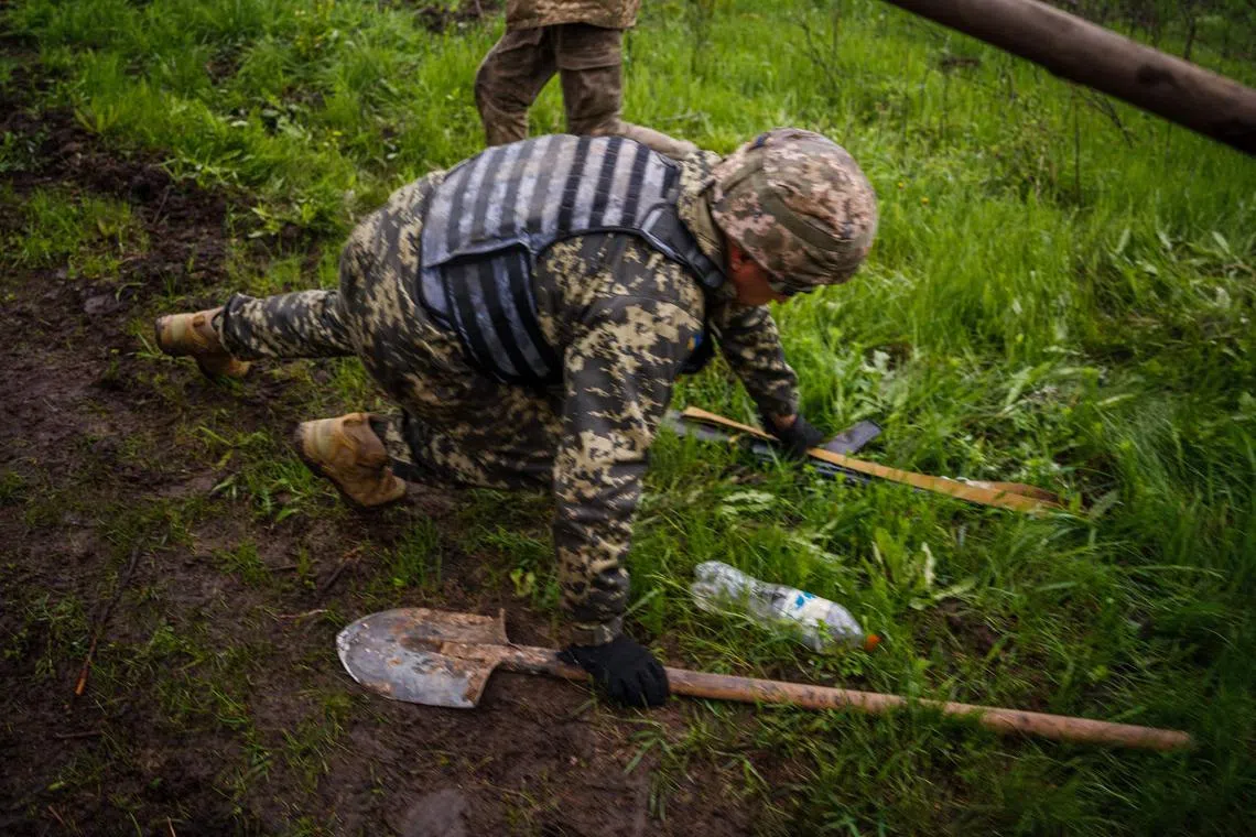 A Ukrainian serviceman drops to the ground to take cover, amid  shelling near the front-line city of Bakhmut, in Ukraine's Donetsk region.