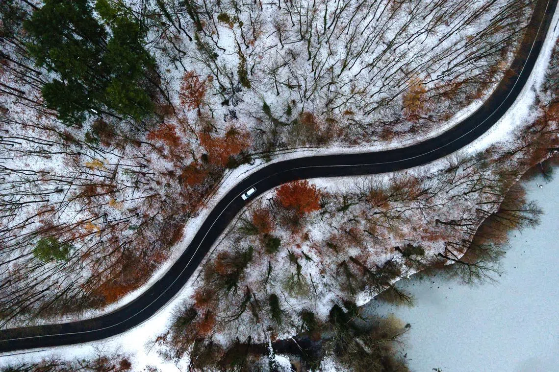 A car travelling slowly through a snow-covered forest near Sikonda, Hungary on Dec 7, 2023. 