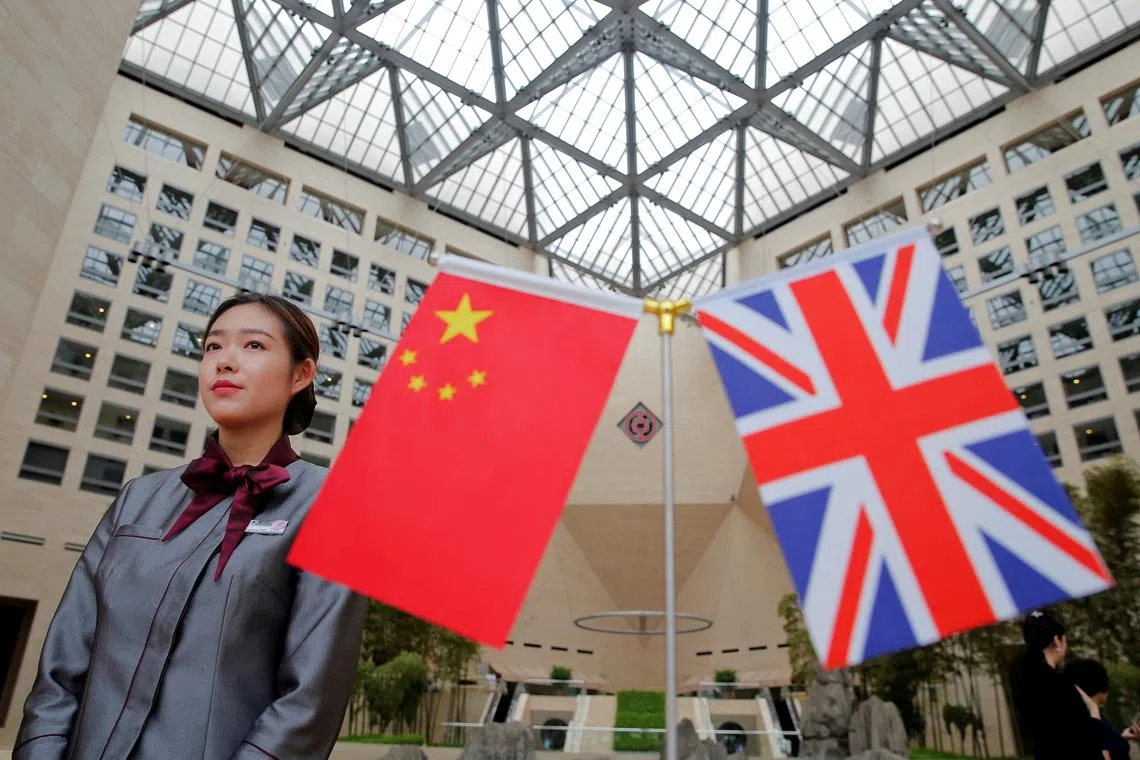 A member of staff stands behind flags as officials arrive for UK-China High Level Financial Services Roundtable at the Bank of China head office building in Beijing, China July 22, 2016. REUTERS/Damir Sagolj/File photo