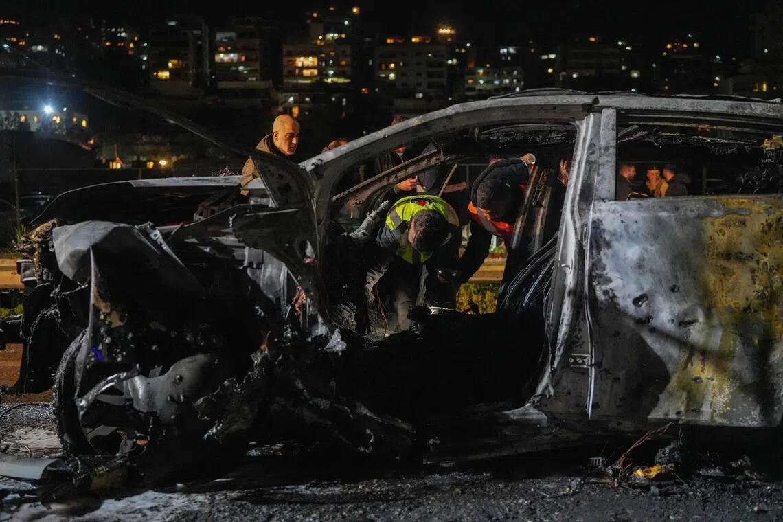 Emergency personnel look into a burned car following a targeted Israeli strike in Khaldeh, Lebanon, on March 31.