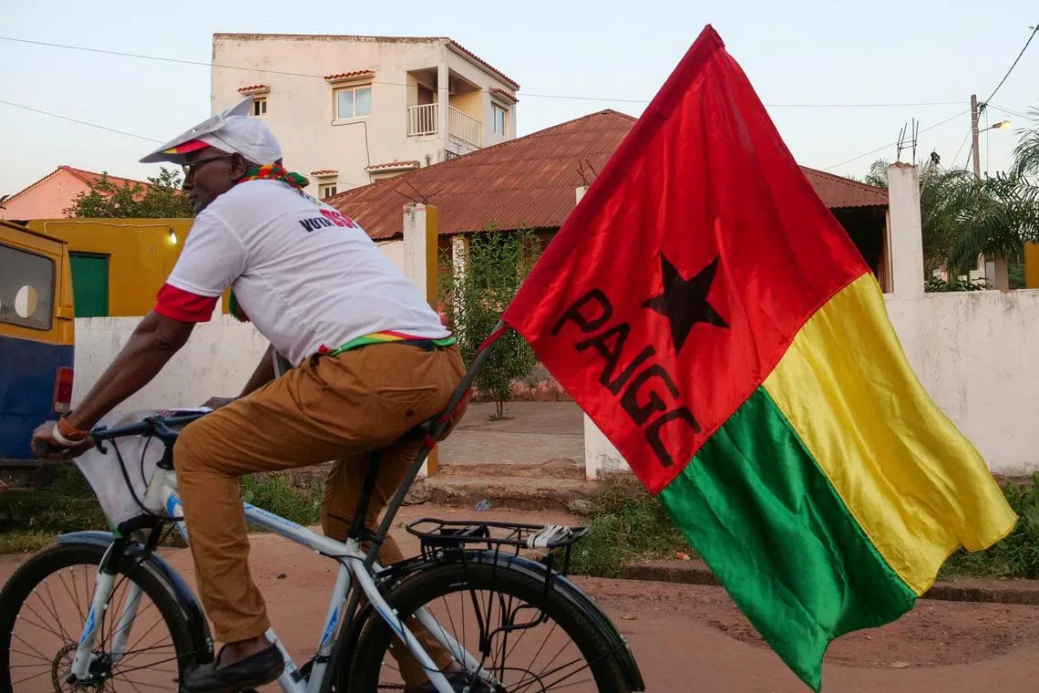 A supporter of presidential candidate Domingos Simoes Pereira rides a bicycle decorated with PAIGC flag, ahead of Sunday's presidential election in Bissau, Guinea-Bissau November 22, 2019. Picture taken November 22, 2019.  REUTERS/Christophe Van Der Perre
