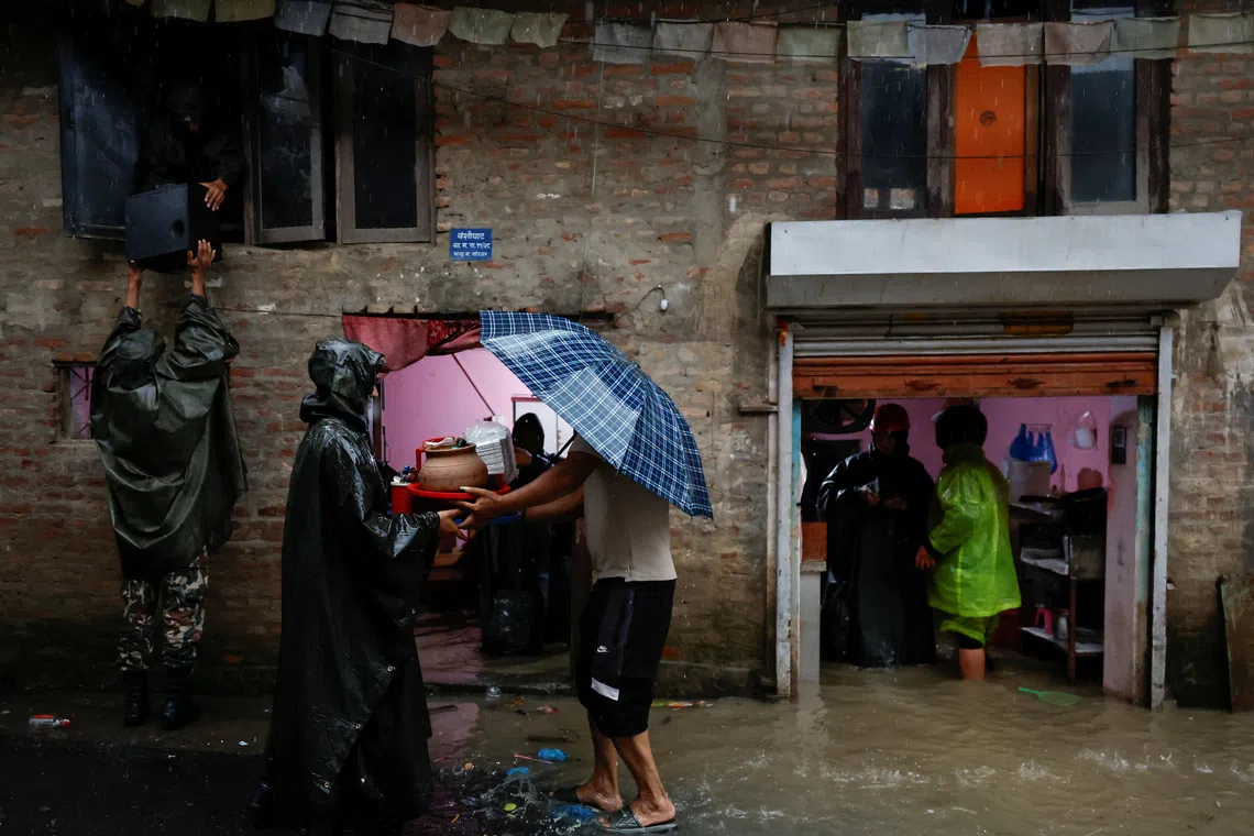 Members of Nepal Army help people retrieve their belongings to a safe area at a flooded street along the bank of overflowing Bagmati River following heavy rains, in Kathmandu, Nepal, October 4, 2025. REUTERS/Navesh Chitrakar
