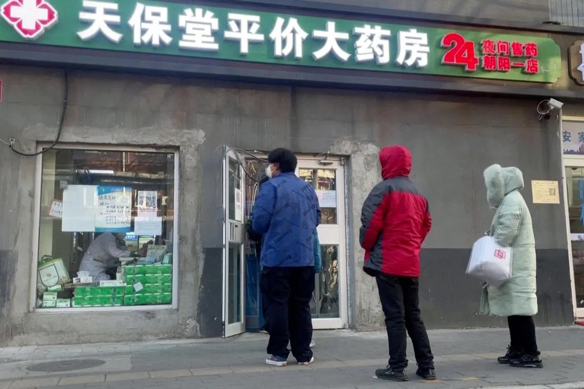 People stand in a queue outside a pharmacy in Beijing, China December 14, 2022, in this screen grab taken from a Reuters TV video. REUTERS TV via REUTERS
