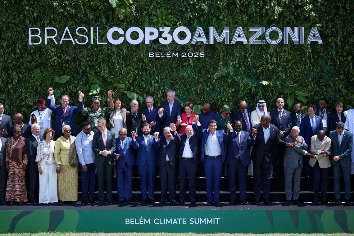 Brazil's President Luiz Inacio Lula da Silva, United Nations Secretary-General Antonio Guterres and other delegates attending the Belem Climate Summit ahead of the United Nations Climate Change Conference (COP30) raise hands as they pose for a family photo, in Belem, Brazil, November 7, 2025. REUTERS/Adriano Machado