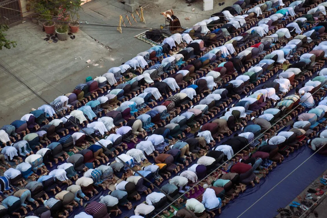 Muslims offer morning prayers to start the Eid al-Fitr festival on a road near destroyed mosques in Mandalay.
