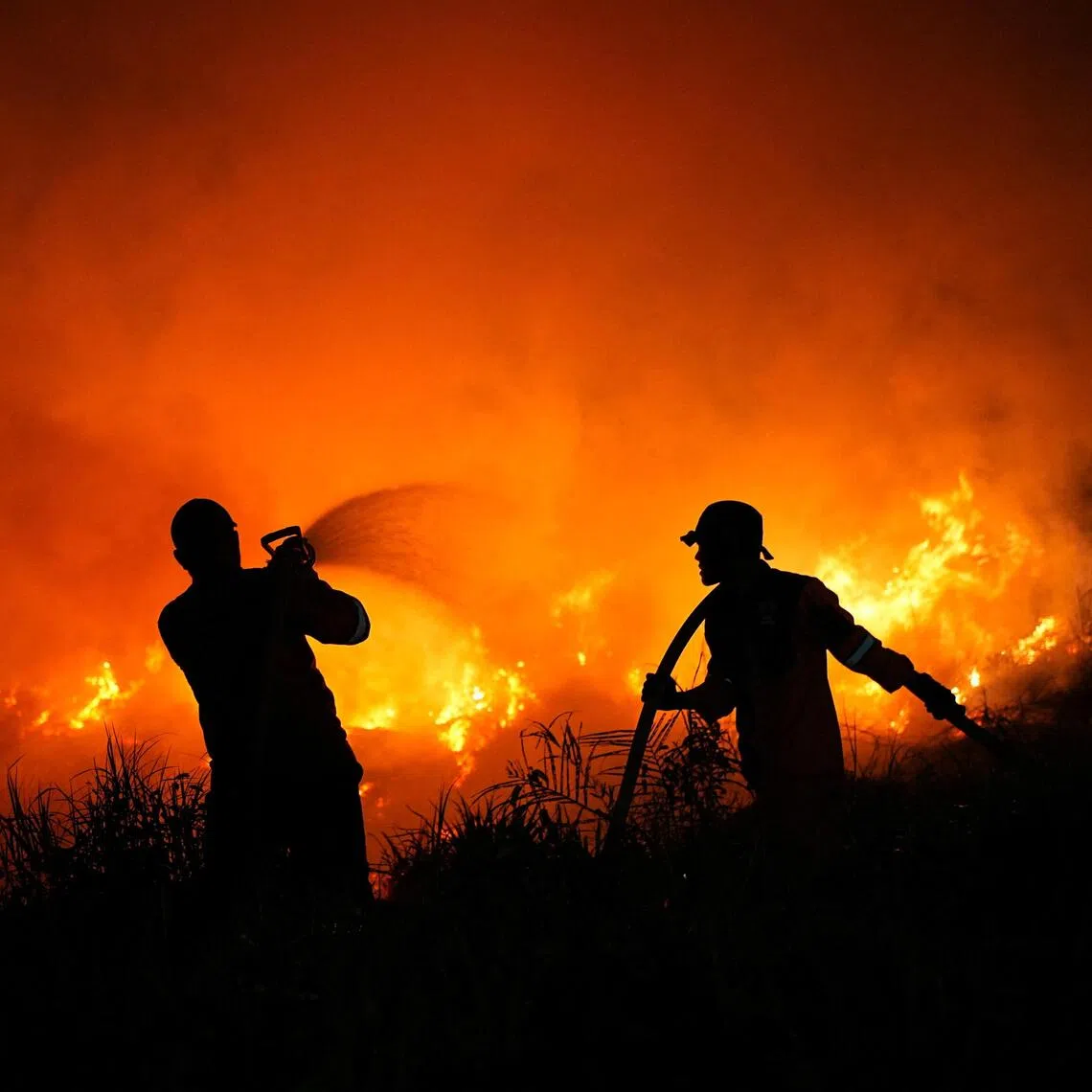 Firefighters spray water in an attempt to extinguish a wildfire near the Palembang-Indralaya toll road in Ogan Ilir, South Sumatra province, Indonesia, on Aug 28.