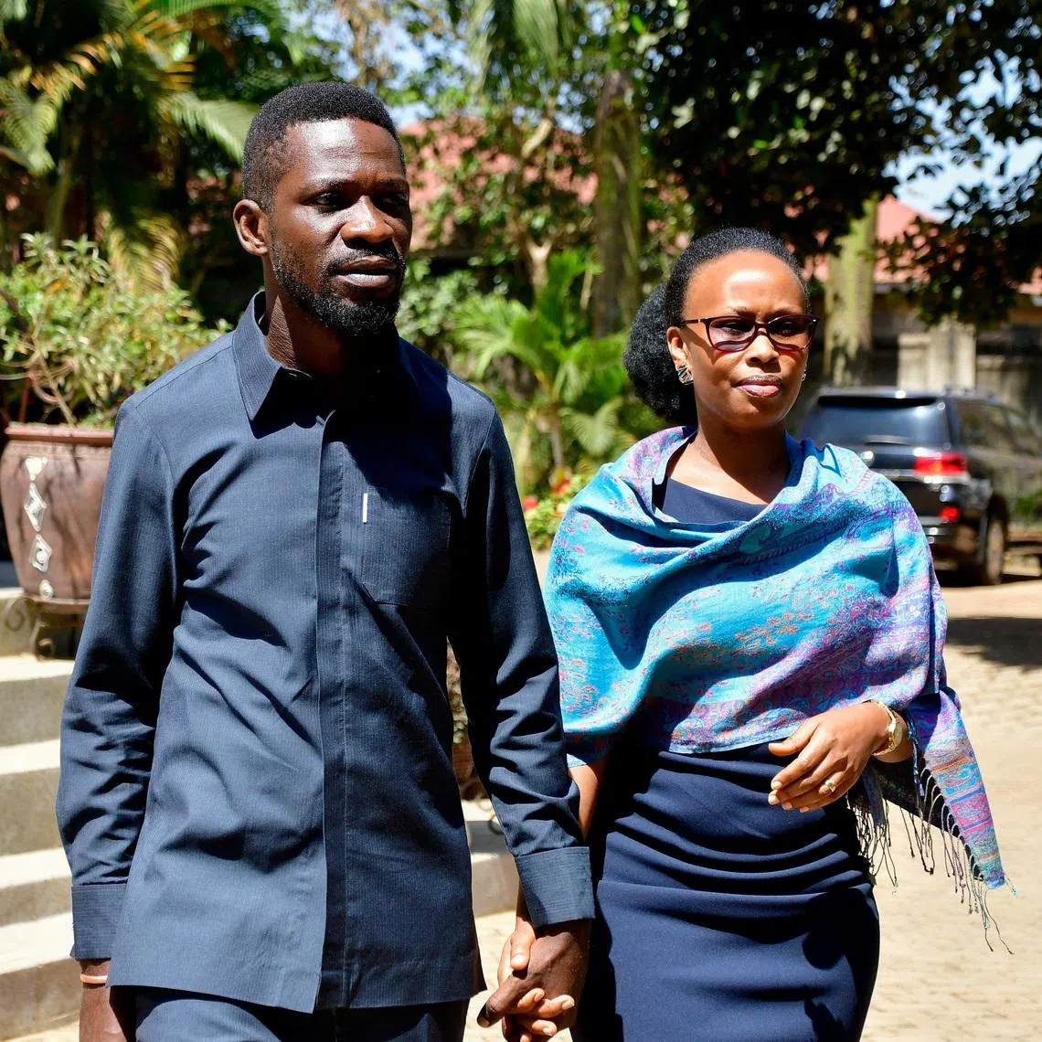 FILE PHOTO: Ugandan Presidential candidate Robert Kyagulanyi, also known as Bobi Wine, of the National Unity Platform (NUP) party, walks with his wife Barbara Kyagulanyi, after he addressed a press conference as they prepare to leave their Magere home to vote in the general election, in Kasangati town near Kampala, Uganda January 15, 2026. REUTERS/Abubaker Lubowa/ File Photo