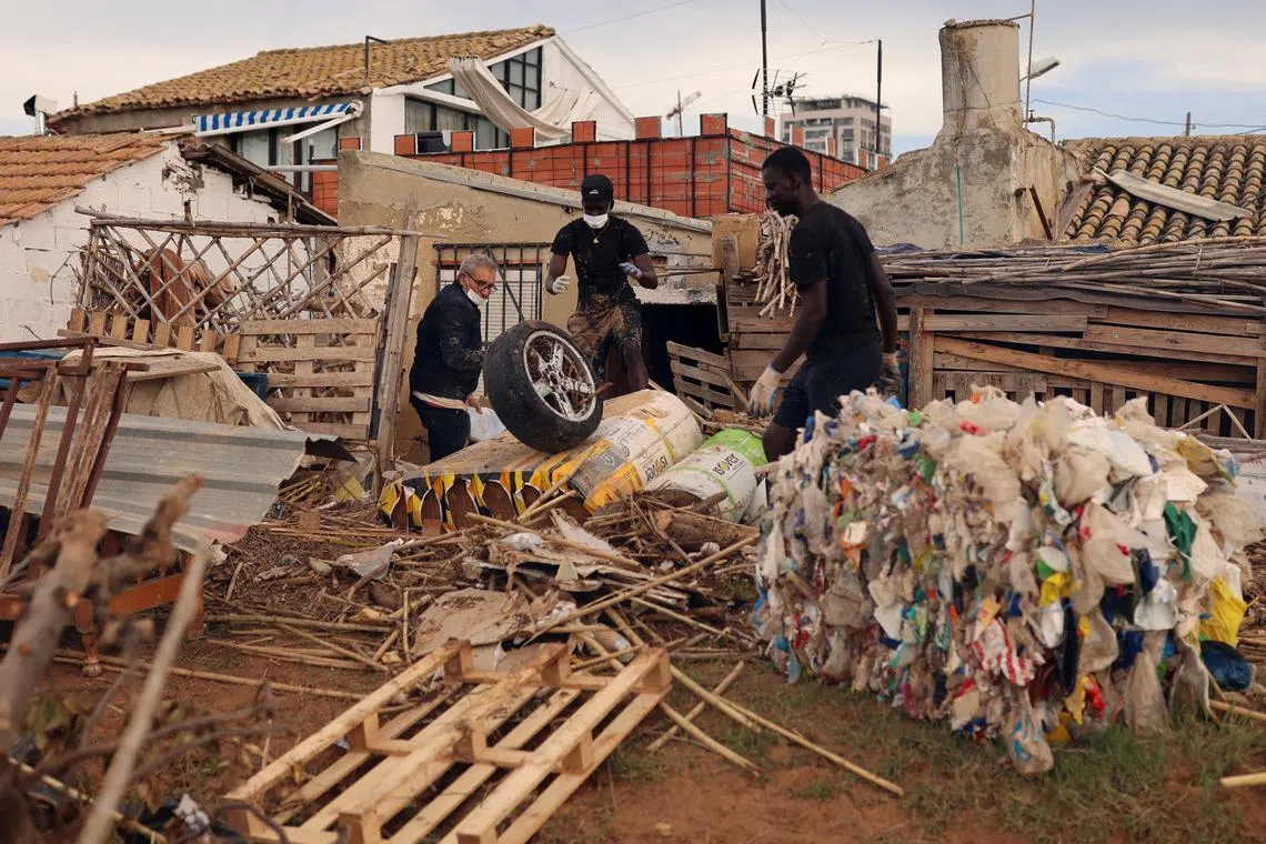 FILE PHOTO: Osman, 26, and his friend Mohamed, 27, from Senegal, work to clean their house, in the aftermath of floods caused by heavy rains, in Valencia, Spain, November 3, 2024. REUTERS/Nacho Doce/File Photo