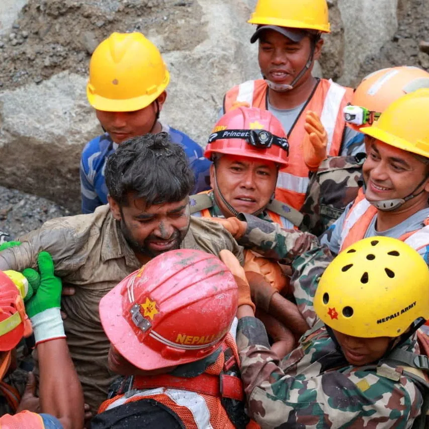 Survivor Sanjay Sah is carried by members of a search and rescue team.