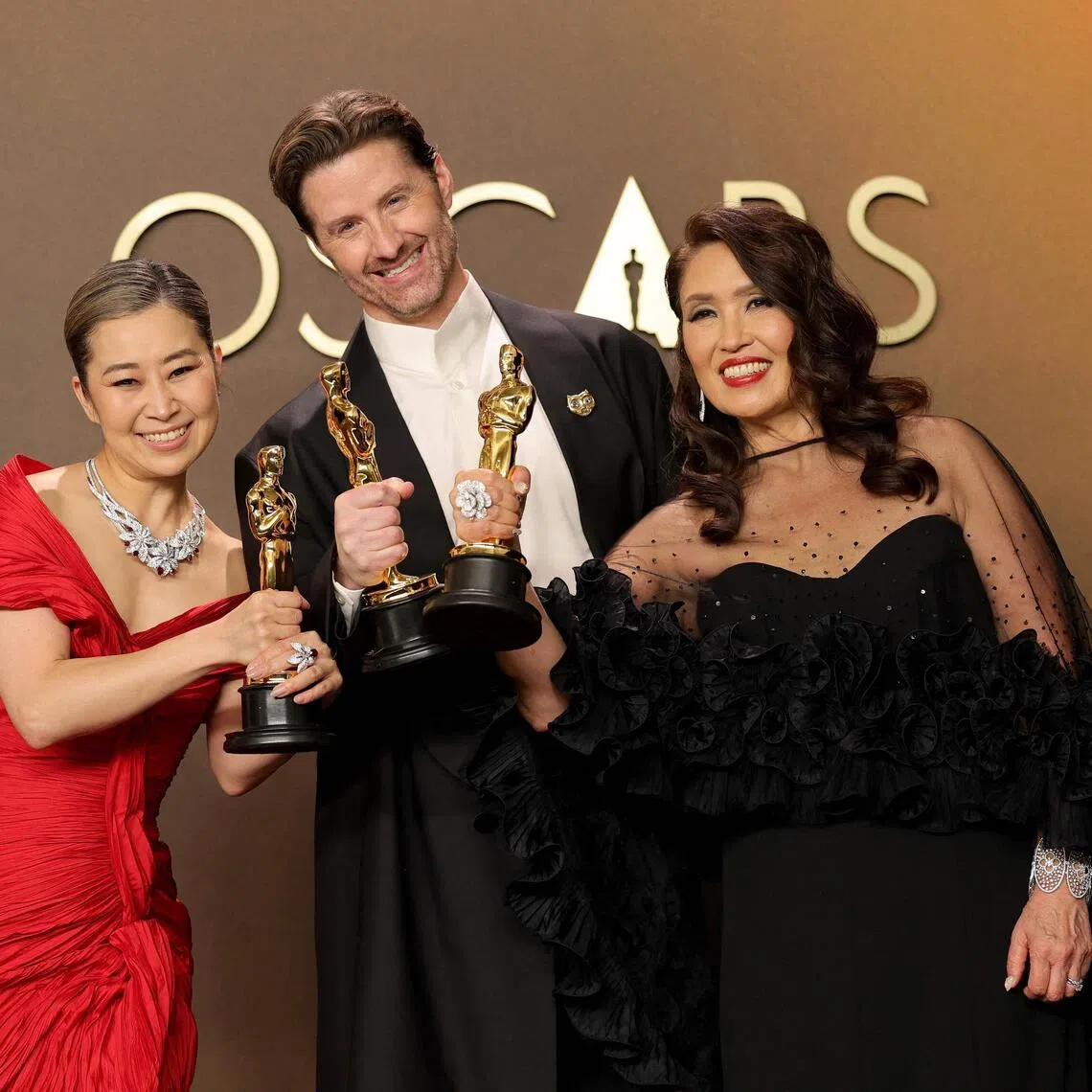 (From left) Maggie Kang, Chris Appelhans, and Michelle Wong, winners of the Best Animated Feature Film Award for KPop Demon Hunters, pose in the press room during the 98th Oscars at Dolby Theatre on March 15.