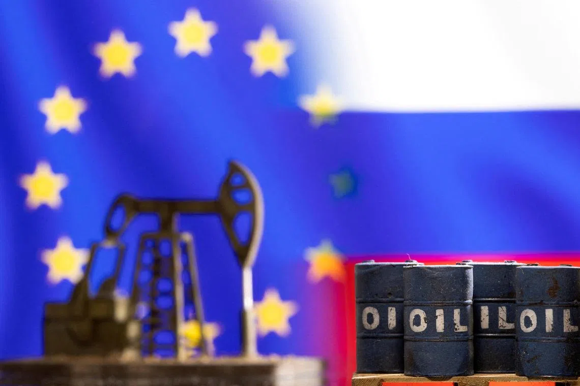 Models of oil barrels and a pump jack are seen in front of displayed EU and Russia flag colours.