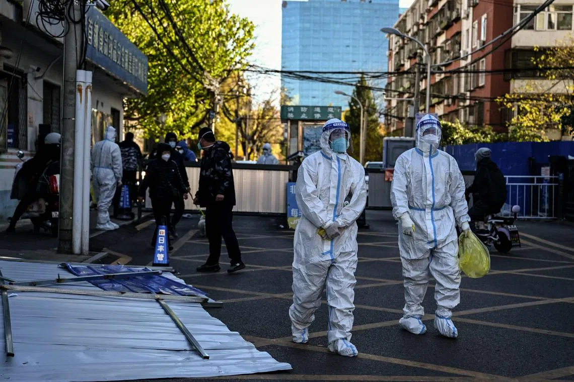 Health workers are seen near a residential area under lockdown due to Covid-19 restrictions in Beijing on Nov 13, 2022. 
