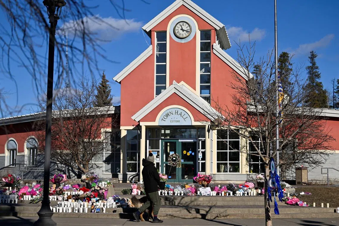 A person visits a growing makeshift memorial on the steps of the town hall, four days after one of the worst mass shootings in recent Canadian history, in the town of Tumbler Ridge, British Columbia, Canada February 14, 2026. REUTERS/Jennifer Gauthier