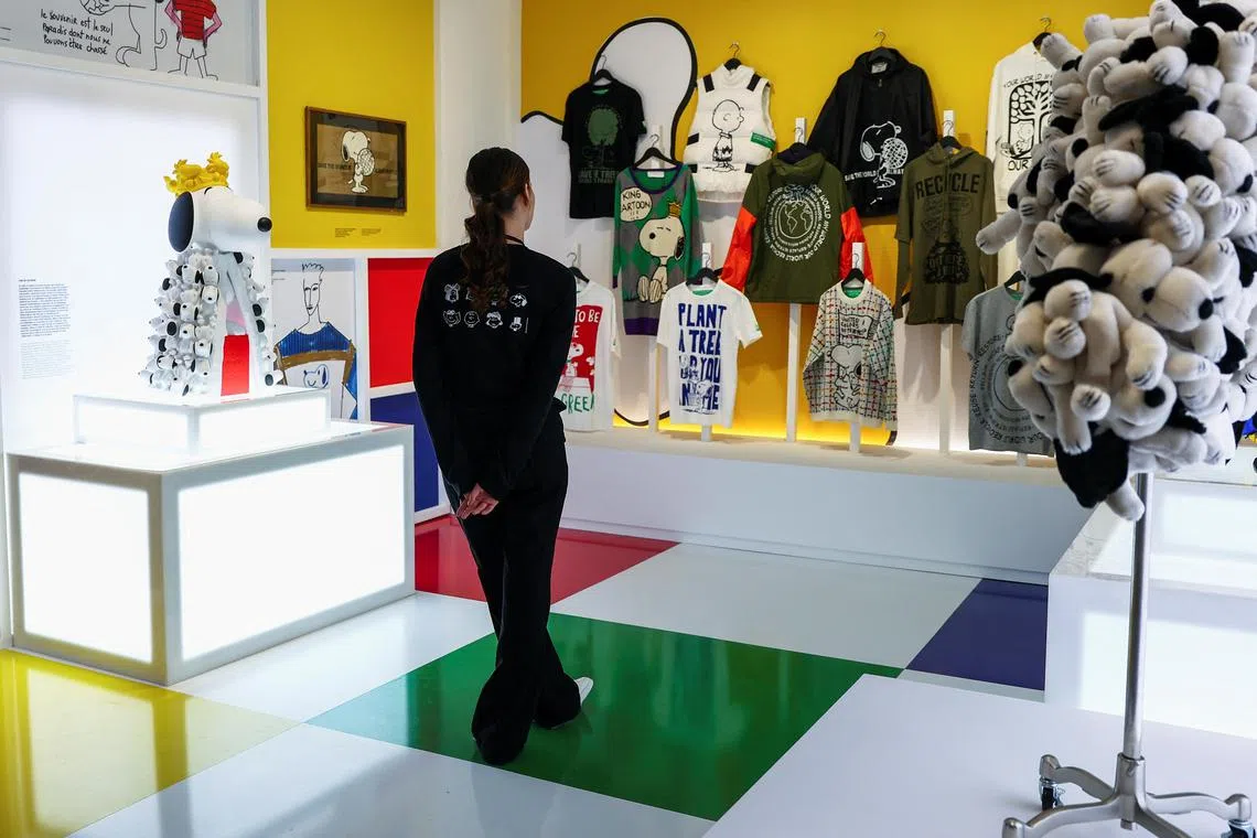 A woman looks at clothes with Snoopy and Charlie Brown, displayed as part of the Snoopy In Style exhibition to mark the Peanuts comic strip's 75th anniversary in Paris on March 20.