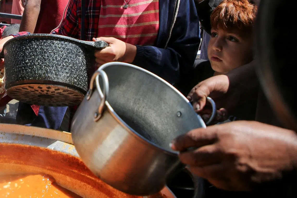 FILE PHOTO: Palestinians gather to receive food cooked by a charity kitchen, amid shortages of aid supplies, after Israeli forces launched a ground and air operation in the eastern part of Rafah, as the ongoing conflict between Israel and Hamas continues, in Rafah, in the southern Gaza Strip May 8, 2024. REUTERS/Hatem Khaled/File Photo