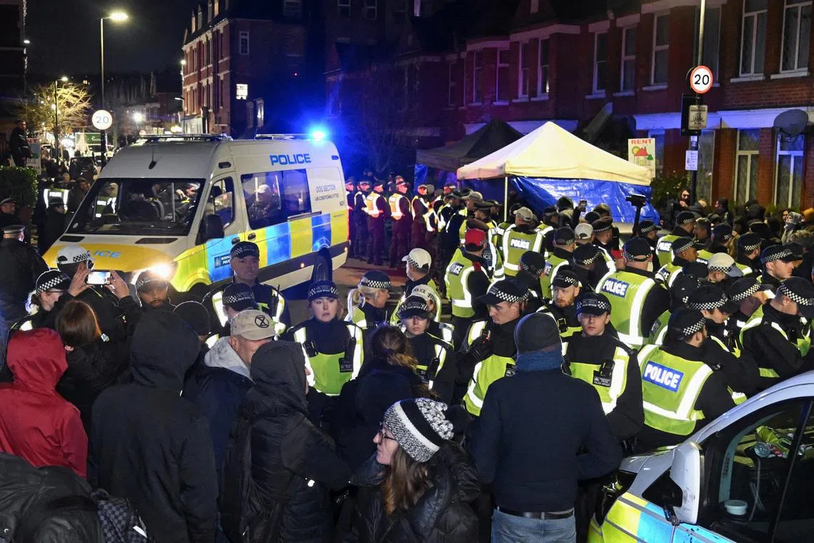 People stand in front of police officers near a Kurdish community centre after a counter terrorism investigation into suspected activity linked to the banned Kurdistan Workers Party, known as the PKK, in London, Britain, November 27, 2024. REUTERS/Jaimi Joy/File Photo