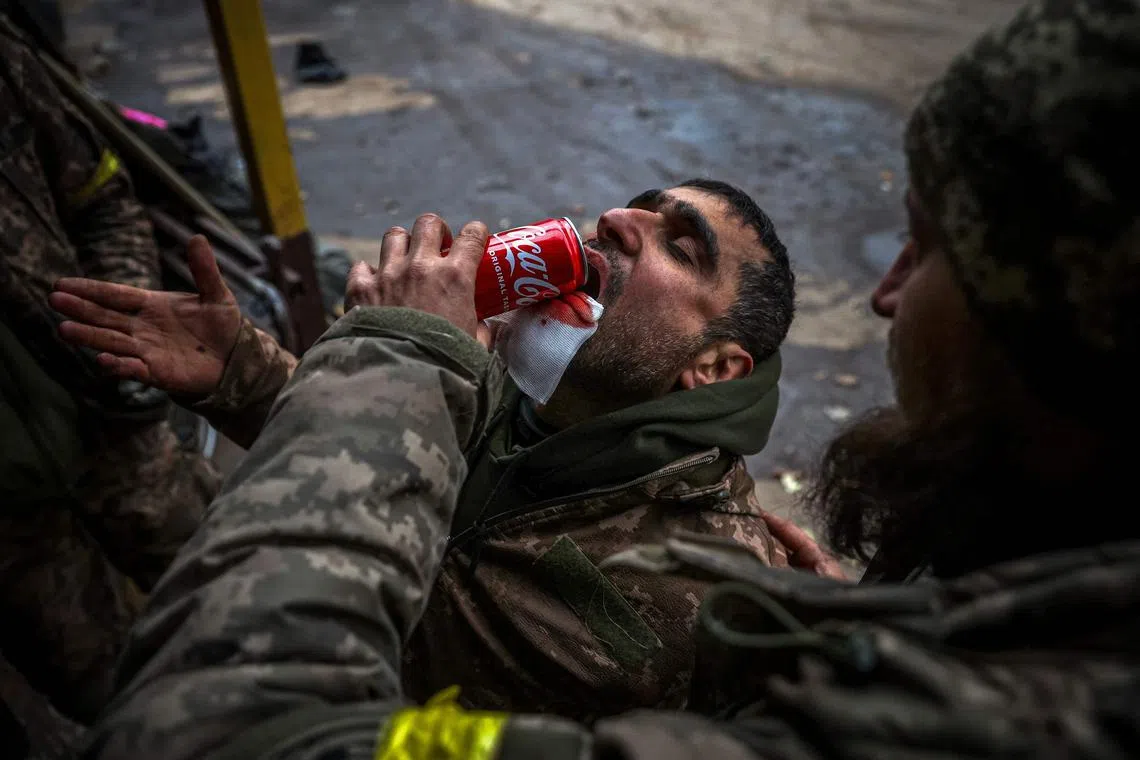 A Ukrainian soldier helps his wounded comrade to drink at a mobile hospital in the vicinity of Bakhmut, in Ukraine's Donetsk region.